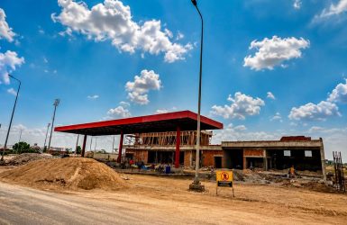 Petrol pump construction project showing a fuel station canopy and forecourt within an active outdoor work environment; the scene conveys practical, professional progress